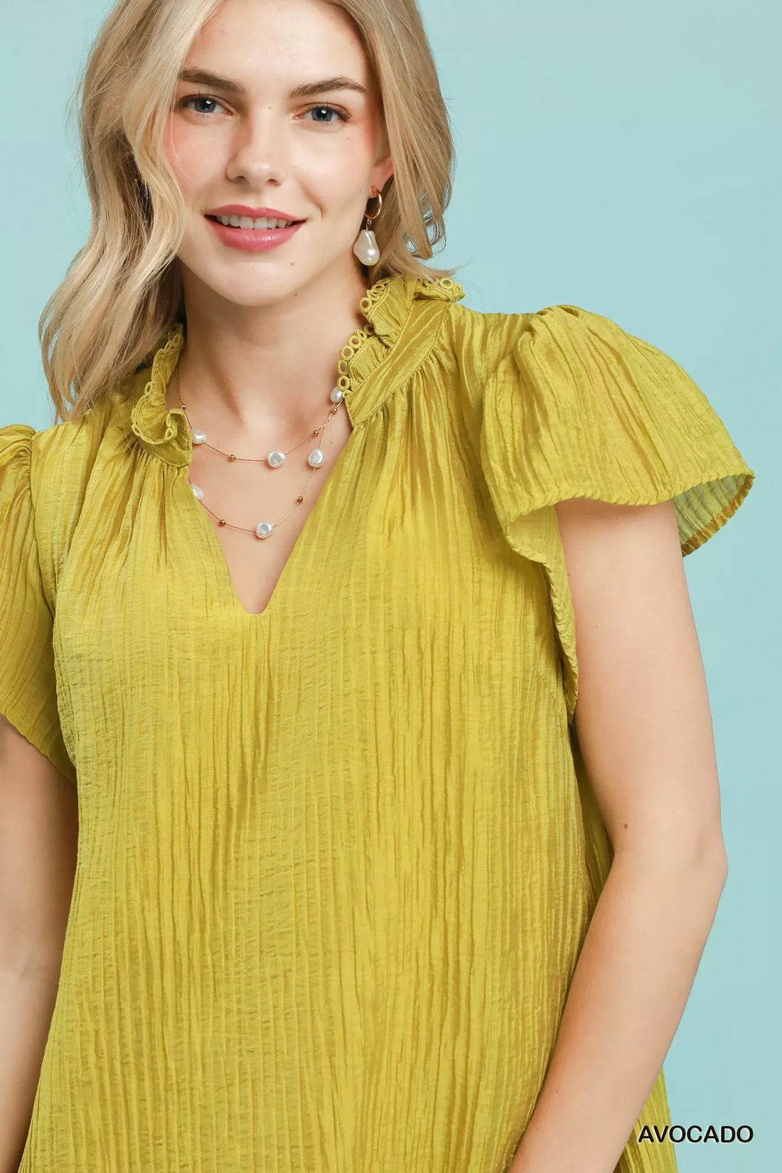 Close-up of Avocado textured mini dress with ruffled collar and V-neck
