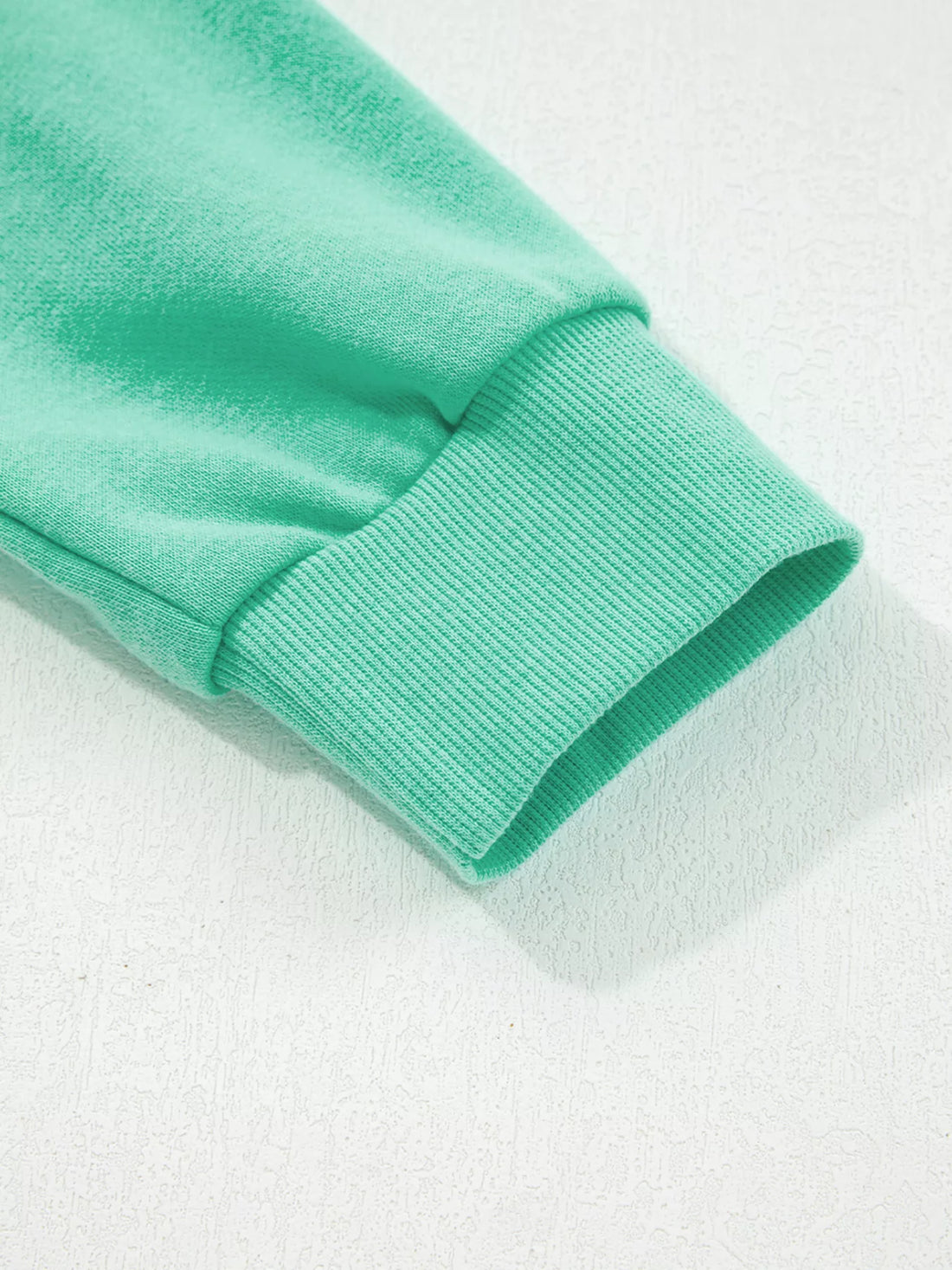 Turquoise sweatshirt sleeve cuff and hem close-up with ribbed trim