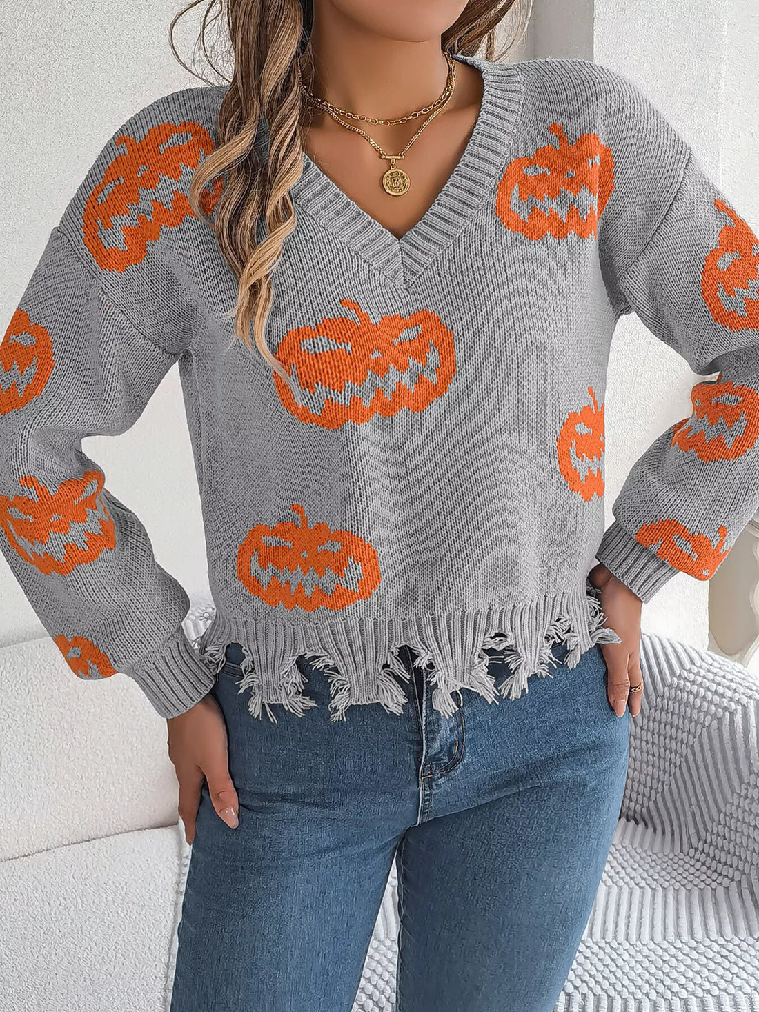 Gray pumpkin sweater with orange knit motifs, V-neck, and fringe distressed hem