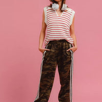 Camouflage track pants with white side stripes, relaxed fit, elastic ankle cuffs.