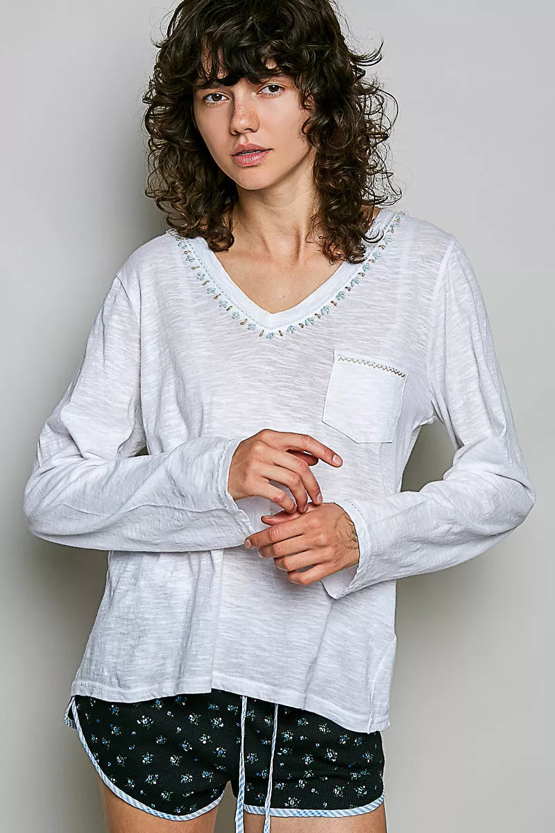 Off white V-neck long-sleeve knit top with contrast hand-stitched trim and chest pocket.