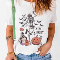 White Halloween graphic T-shirt front featuring skeleton, jack-o'-lanterns, and 'STAY SPOOKY'