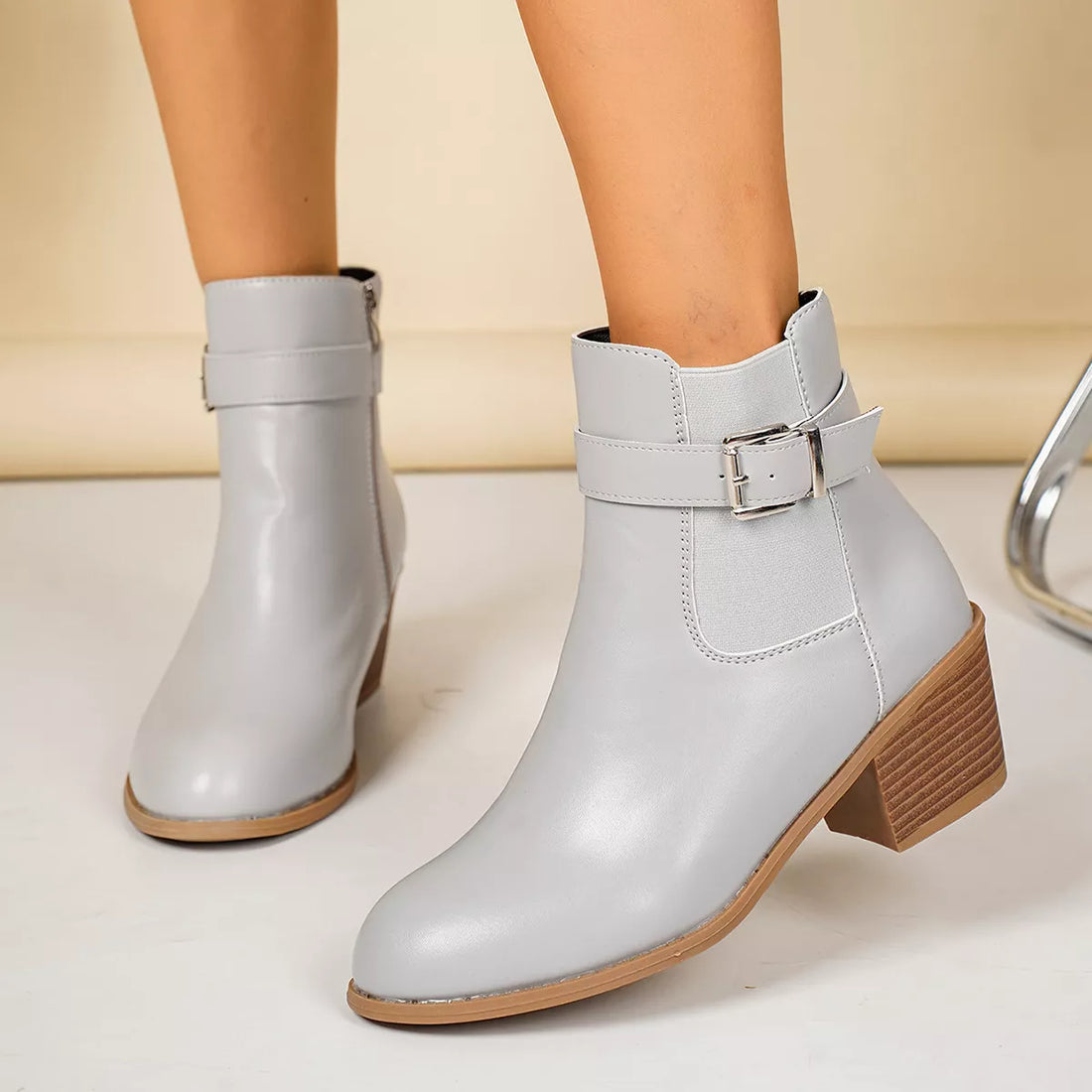 Light gray point-toe block heel ankle boots with buckle strap and stitched seam
