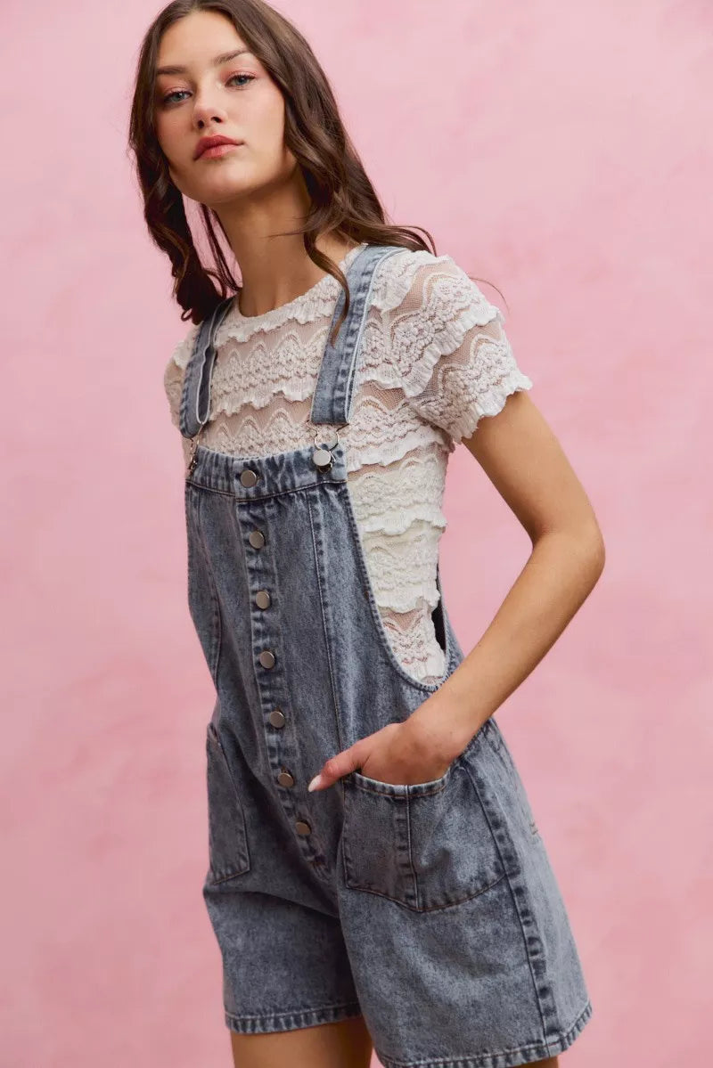 Light wash denim overall romper with adjustable straps and front buttons, wide leg shorts