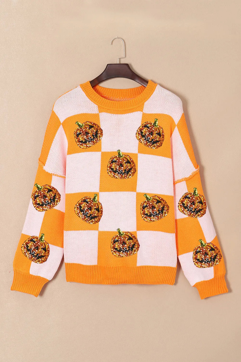 Checkered round-neck sweater with orange-and-white squares and glitter pumpkin applique