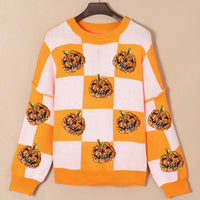 Checkered round-neck sweater with orange-and-white squares and glitter pumpkin applique