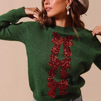 Green Christmas sweater featuring layered red sequin bow ribbon embellishment