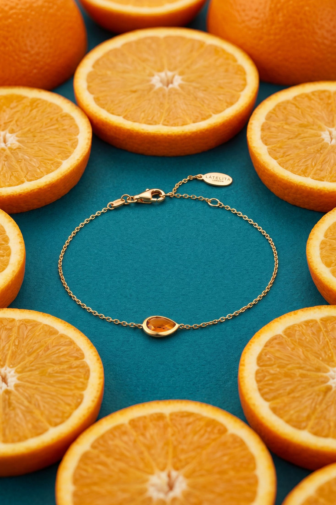 Gold mini teardrop bracelet with amber teardrop charm, flat lay
