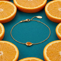 Gold mini teardrop bracelet with amber teardrop charm, flat lay