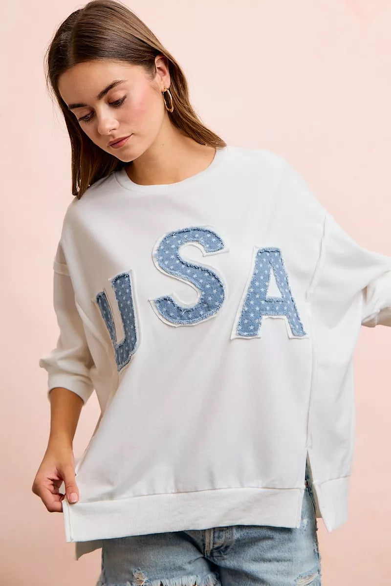 Ivory french terry top featuring large blue "USA" appliqued letters and cuffed sleeves