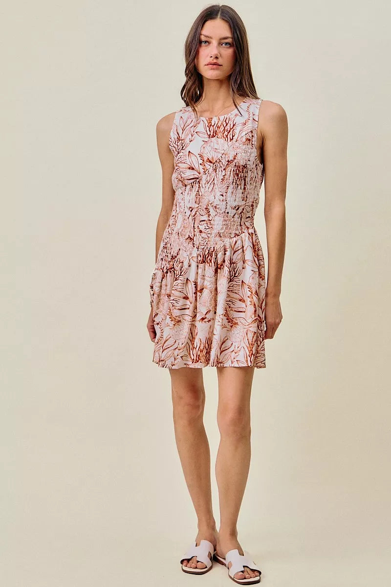 Full front view of coral and white shell-print sleeveless mini dress with smocked bodice