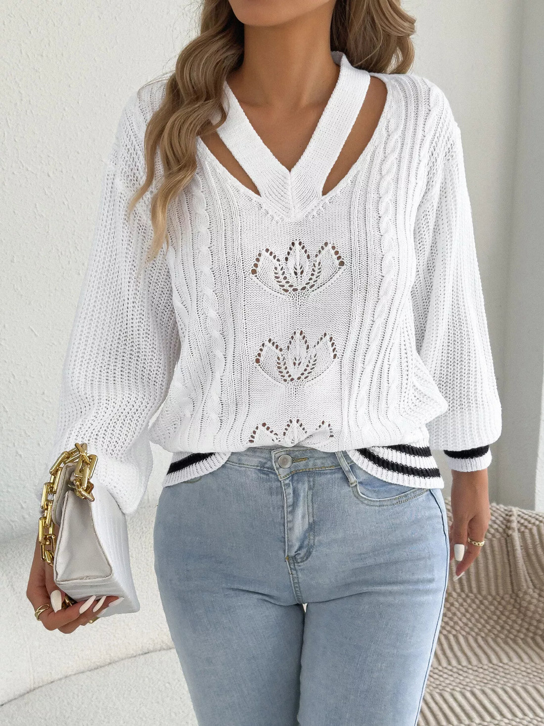 White cutout cable knit sweater with V-neck cutout and three lotus-style knit motifs