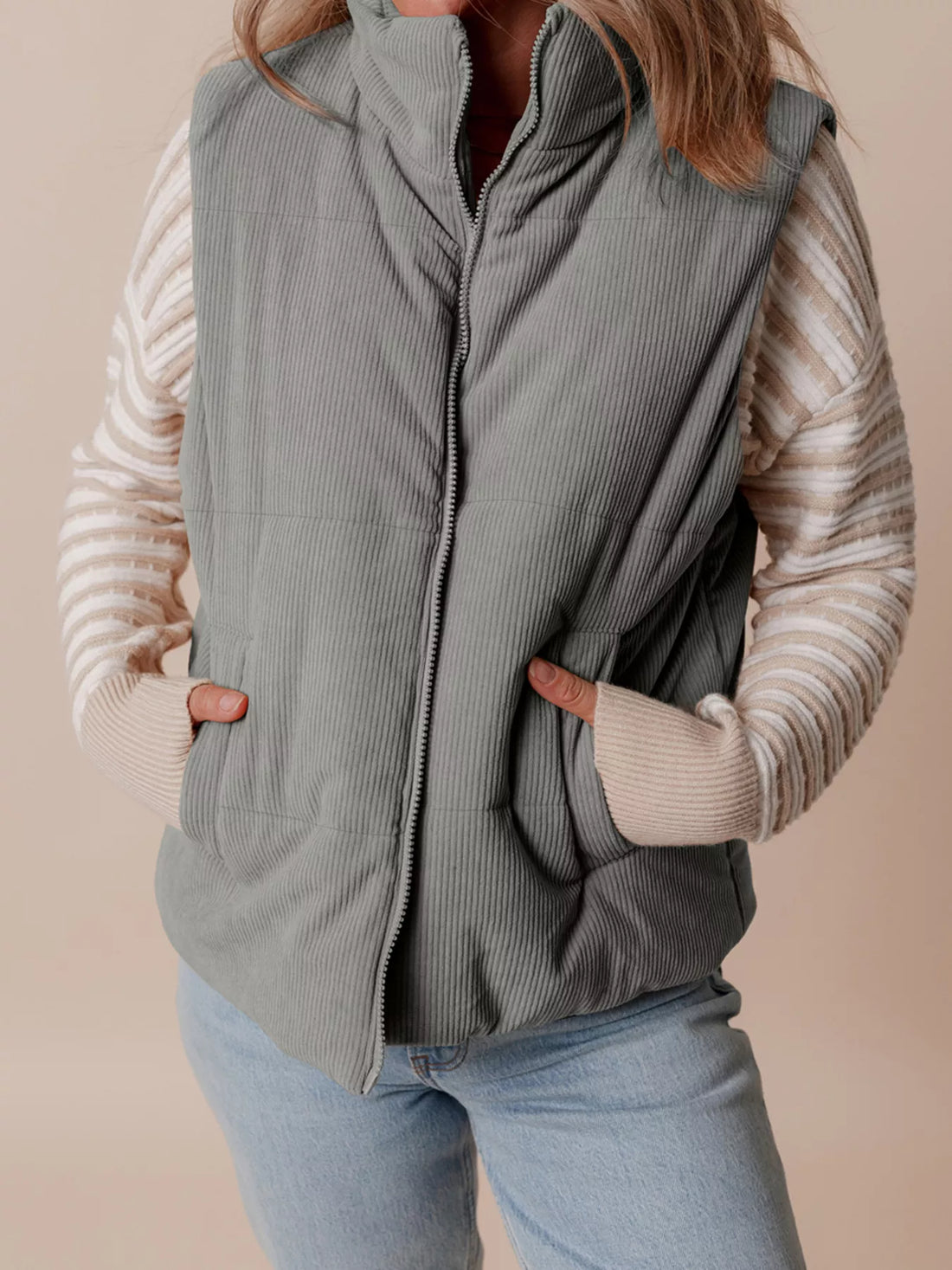 Gray corduroy stand-neck puffer vest with full-length front zipper and ribbed texture.