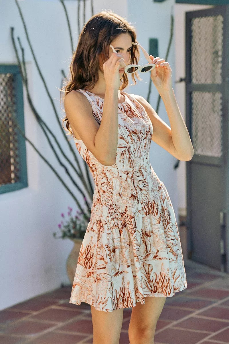 Smocked fit-and-flare mini dress with coral and white shell print, sleeveless round neck