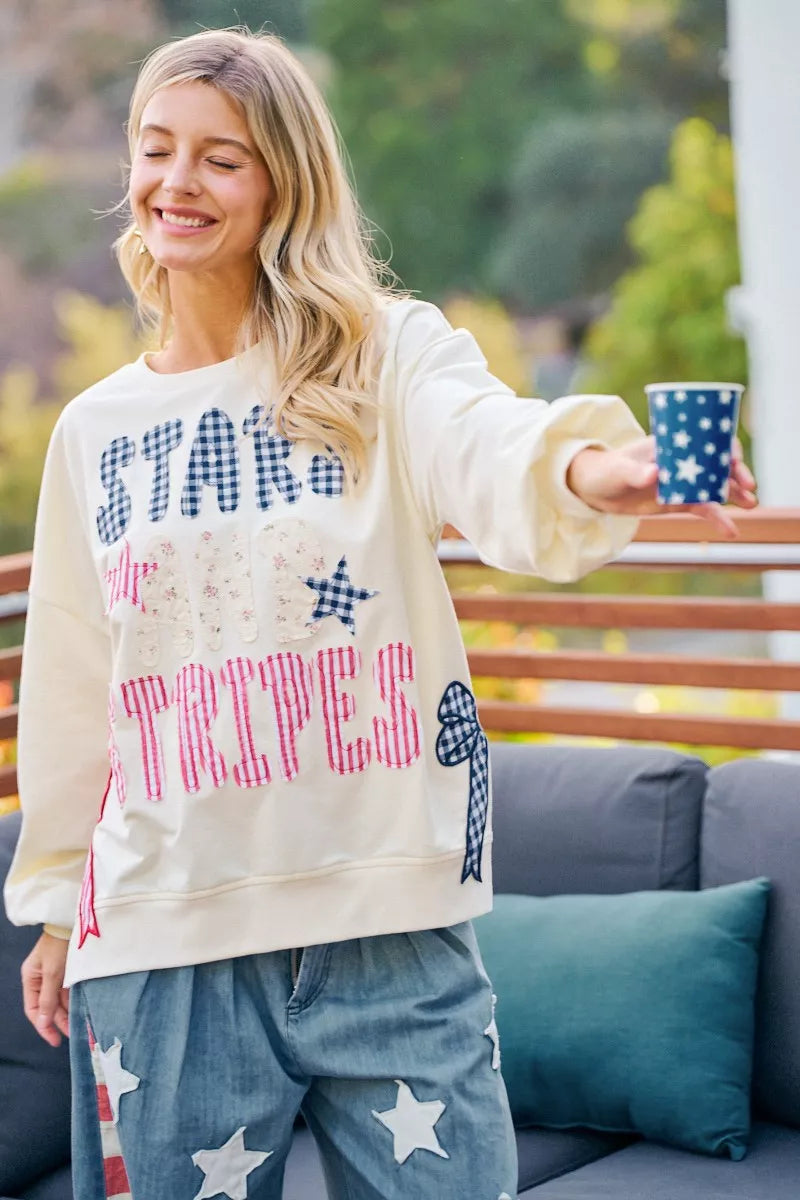 Cream crewneck sweatshirt with stars-and-stripes patch-style graphic, front detail