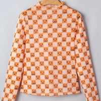 Orange-and-white Halloween blouse on hanger with mock neck, long sleeves, jack-o’-lantern checker print