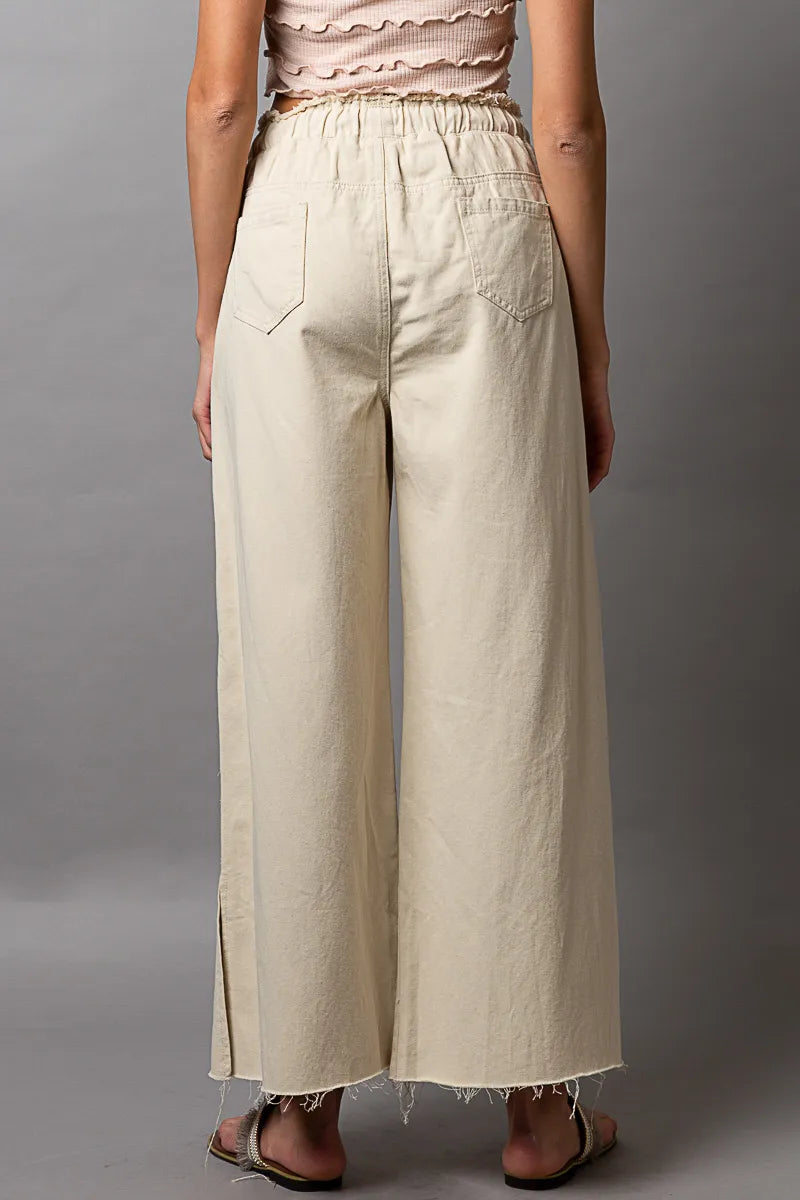 Cream wide-leg drawstring pants with distressed hems and relaxed straight legs