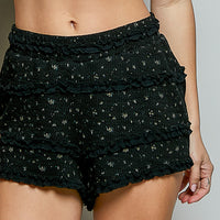 Black ruffled shorts close-up, tiered texture with tiny speckled print