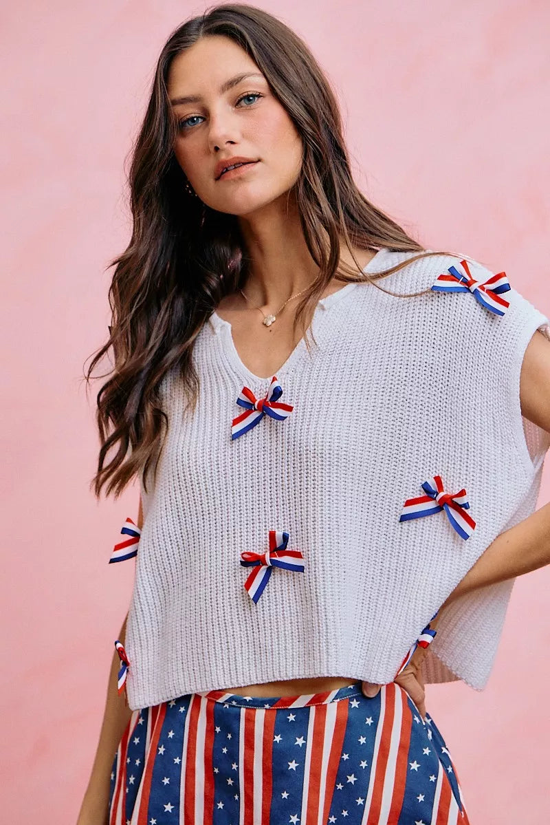 Off-white dolman sweater top with scattered ribbon bow appliques and wide neckline