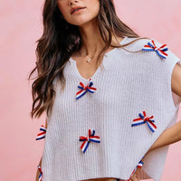 Off-white dolman sweater top with scattered ribbon bow appliques and wide neckline