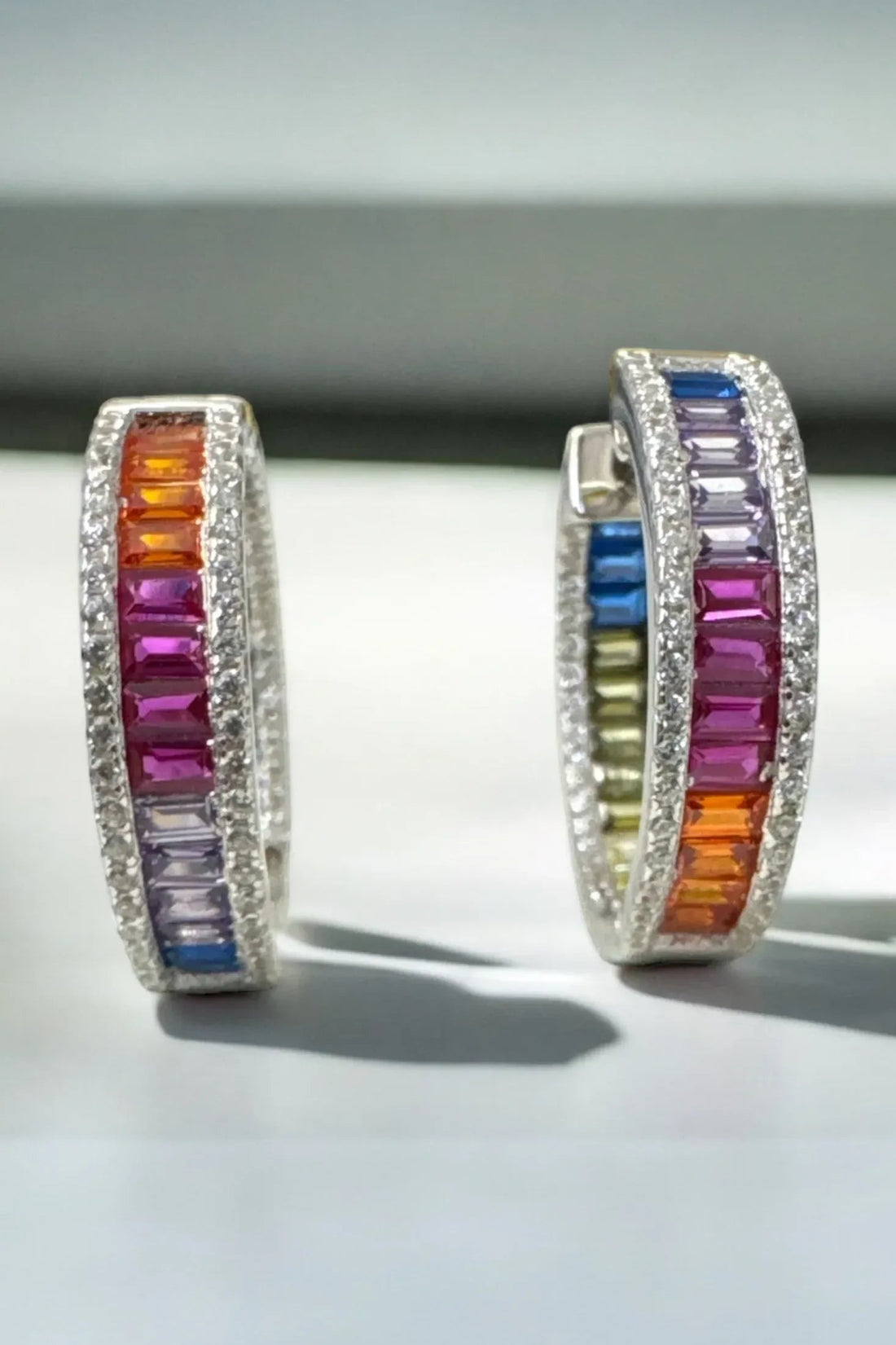 Silver hoop earrings featuring rainbow baguette gemstone stripe and shimmering border