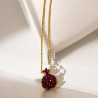 Gold pendant necklace with ruby-pink pomegranate charm in dark red crystal-set bezel