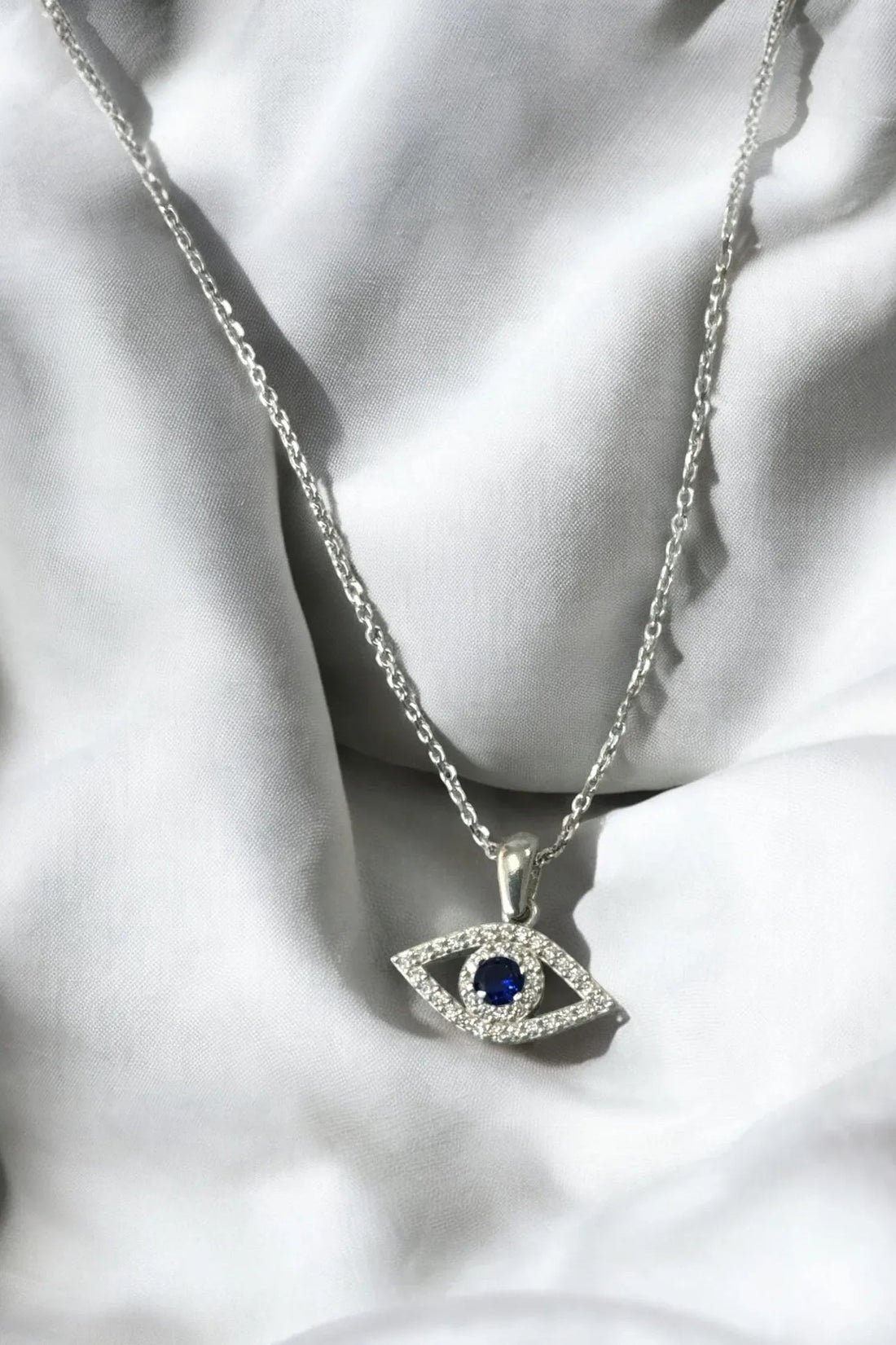 Rhinestone oval evil-eye necklace pendant with blue center stone on silver chain.