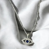Rhinestone oval evil-eye necklace pendant with blue center stone on silver chain.