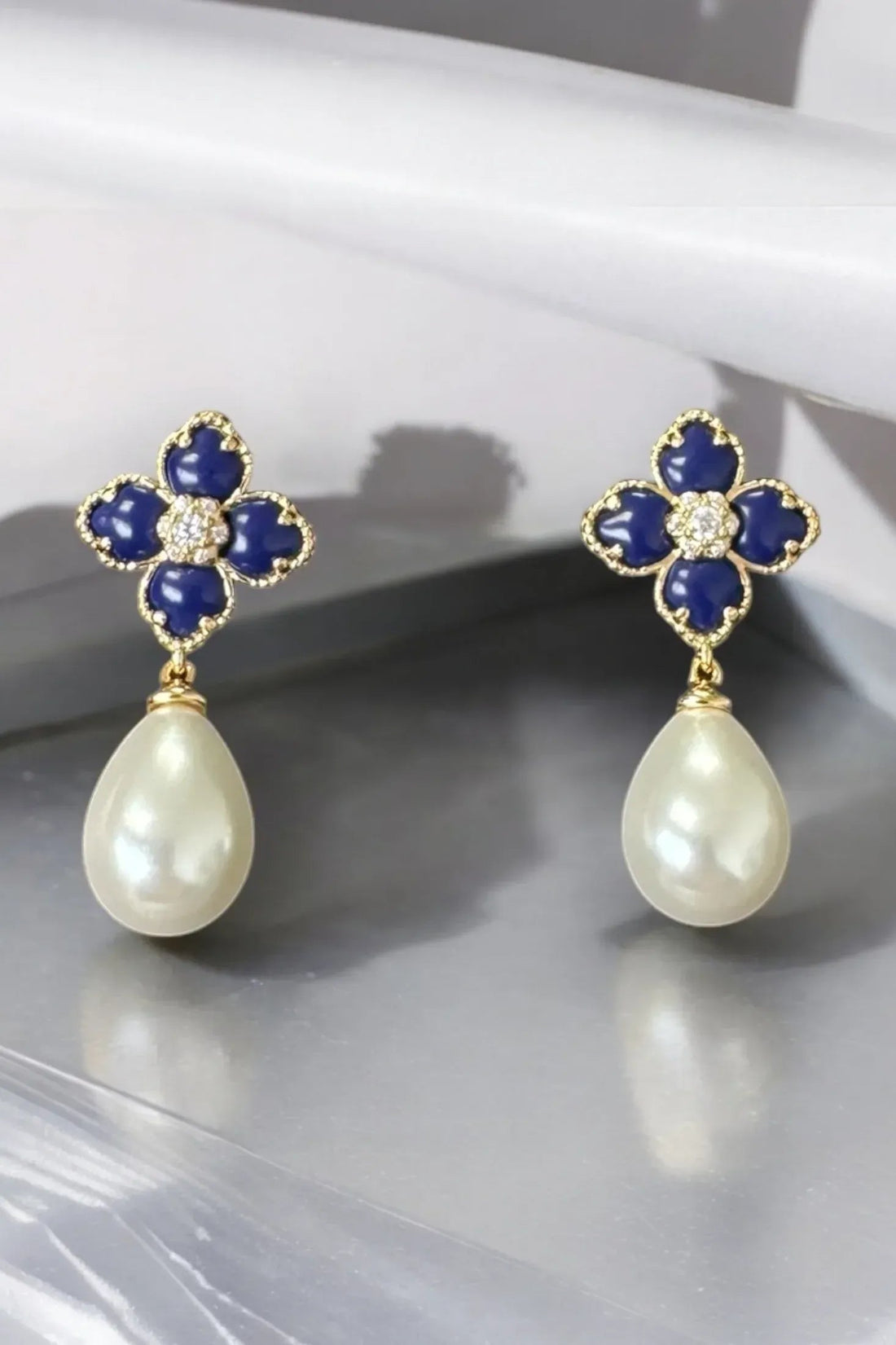 Gold-tone clover flower drop earrings with navy enamel petals and white pearl dangles