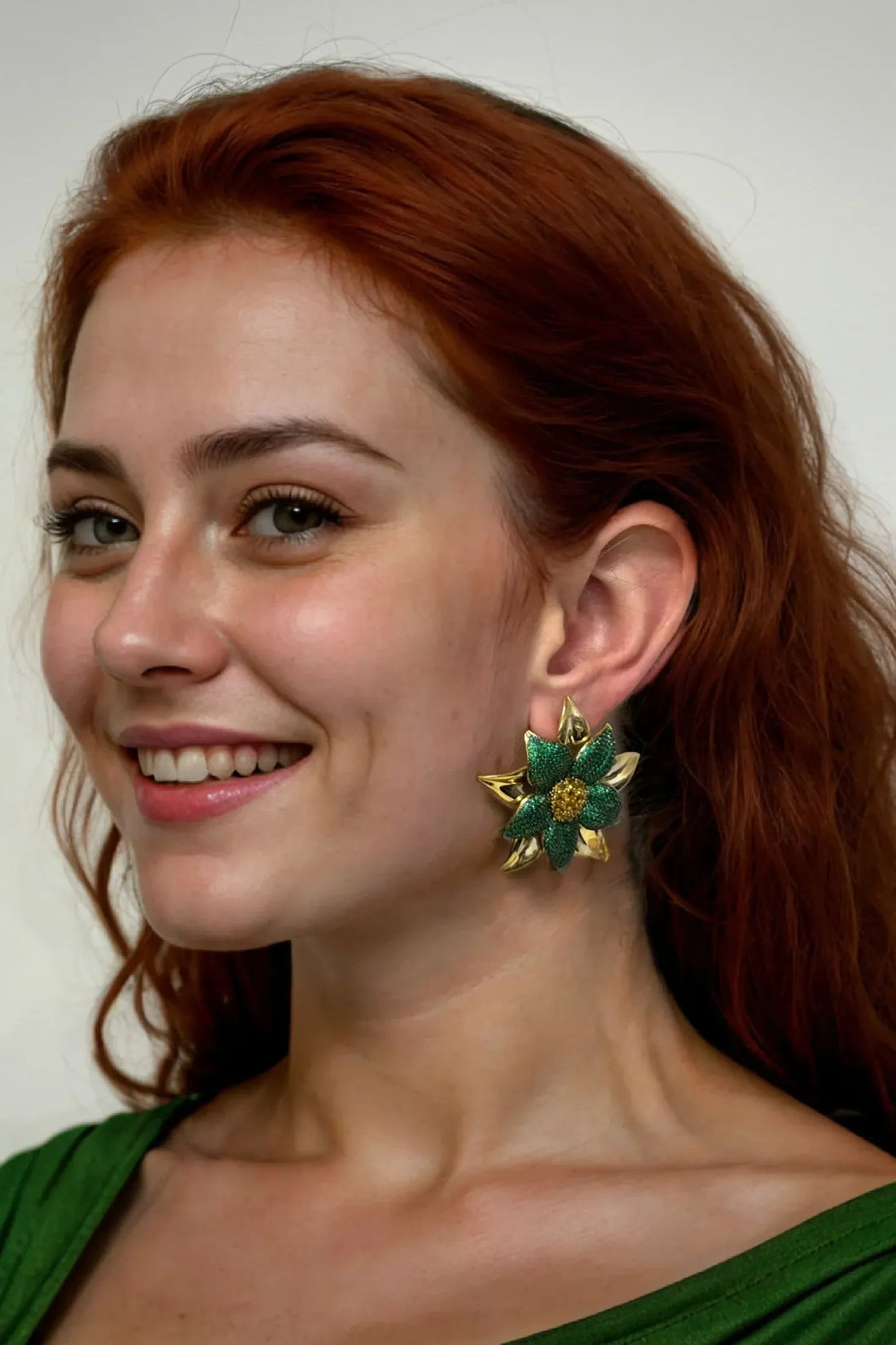 Green flower stud earrings on model ear, gold petals with yellow center