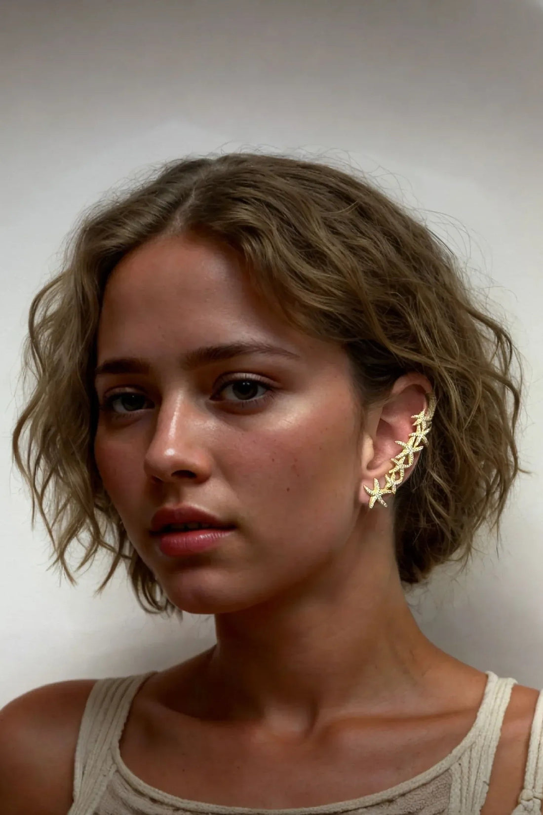 Gold starfish ear climber earring with stacked star shapes on left ear