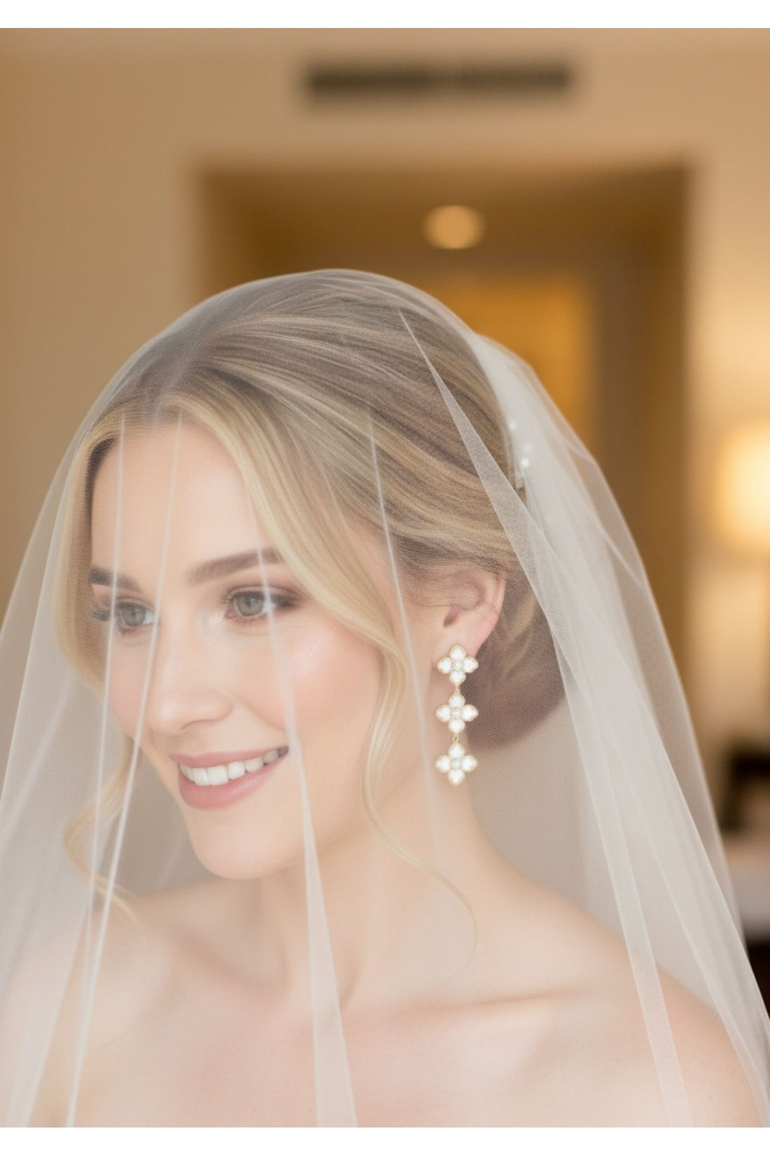 Gold mother-of-pearl clover triple-drop earrings on a bride under a veil
