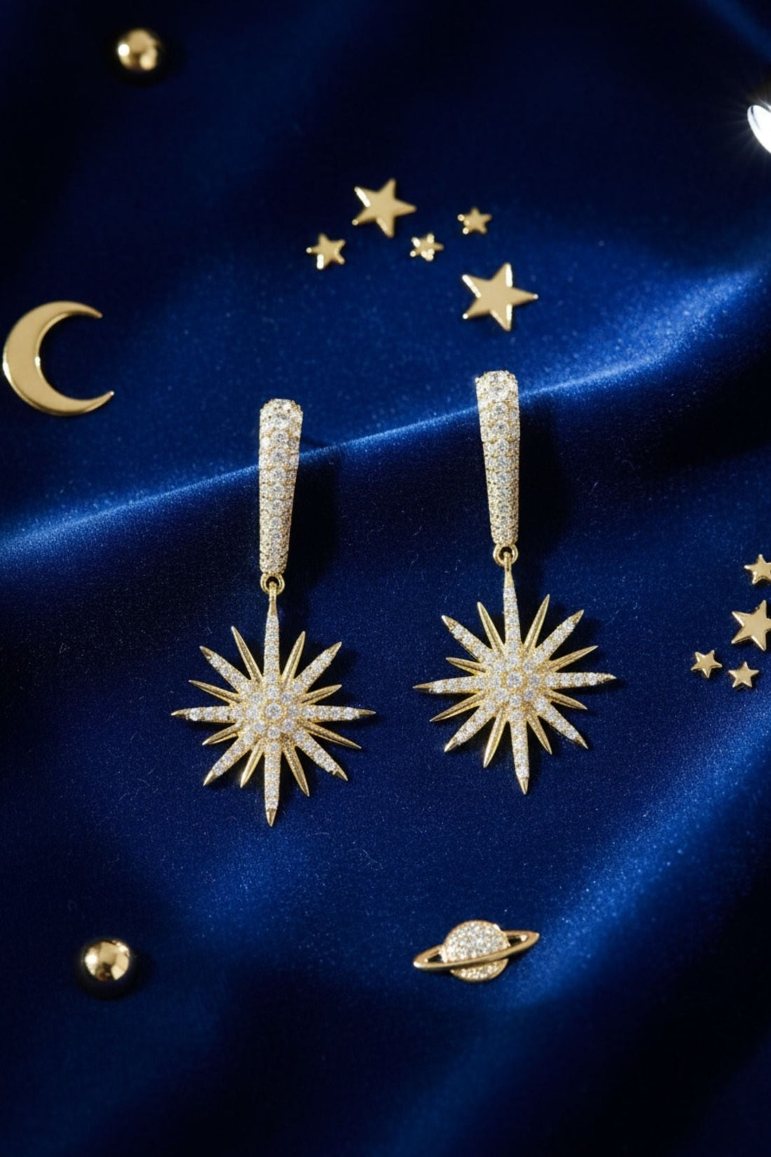 Pair of gold starburst drop earrings with crystal sunburst centers and slim dangling posts