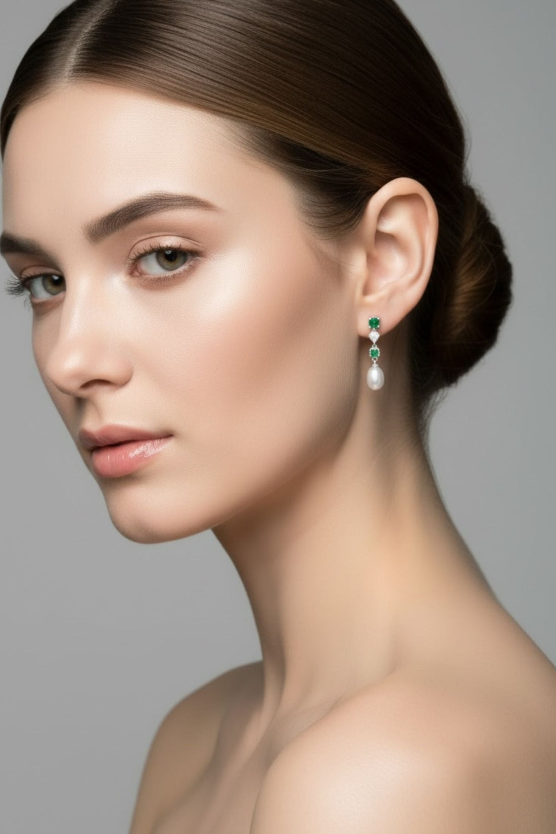 Green stone and white pearl drop earrings worn on ear, silver-tone setting