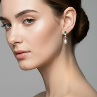 Green stone and white pearl drop earrings worn on ear, silver-tone setting