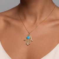 Gold hamsa pendant necklace worn on neck with blue opal-style center stone