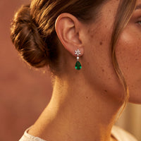 Silver crystal dangle earrings with emerald-green teardrop stones on ear