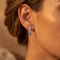 Silver drop earrings on ear with teal pear-shaped stone and tiny crystal stud