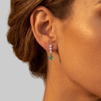 Silver drop earrings on ear with teal pear-shaped stone and small sparkle cluster