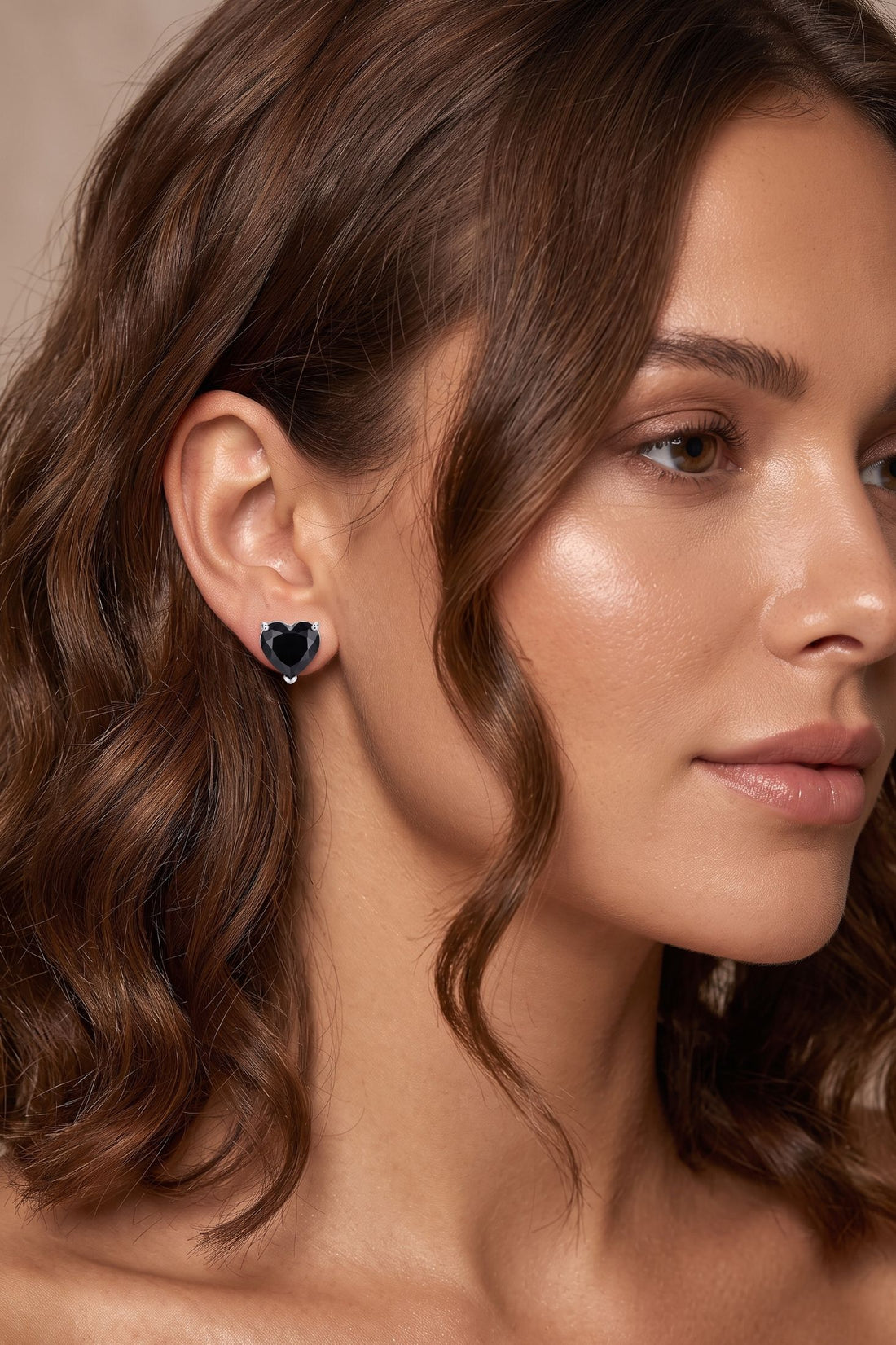Heart stud earrings with black gemstone, worn on model ear