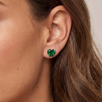 Silver heart stud earrings with emerald-green gemstone on ear
