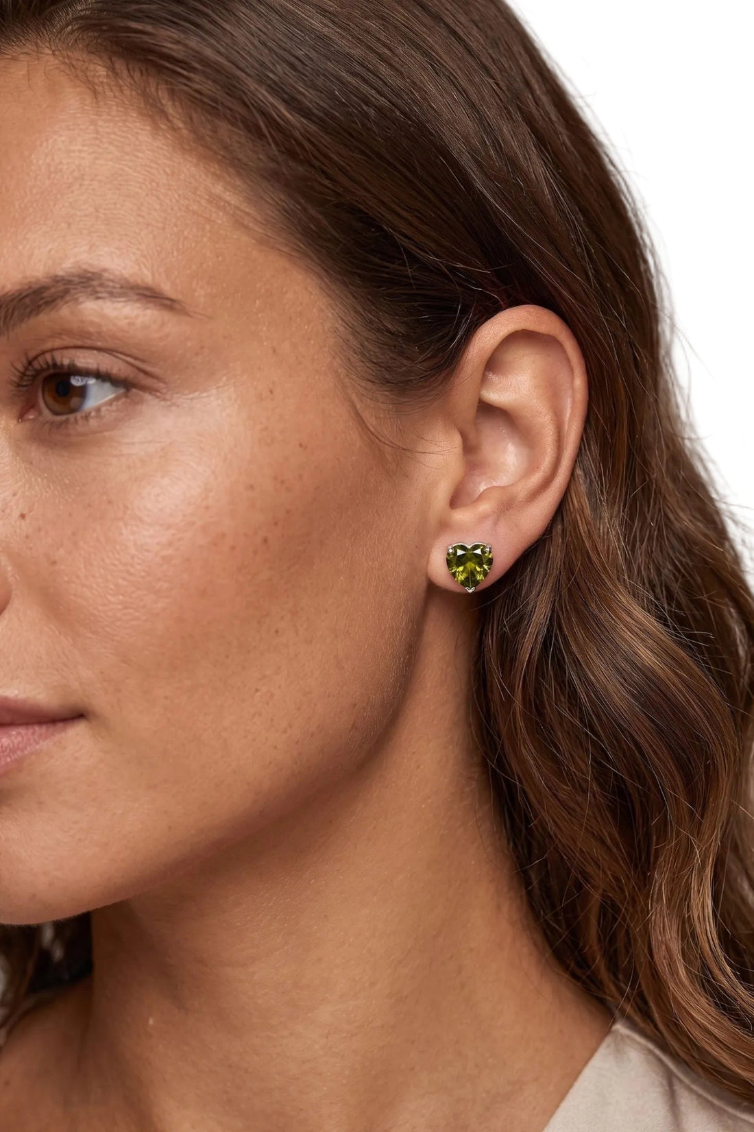 Silver heart stud earrings with peridot-green gemstone on ear