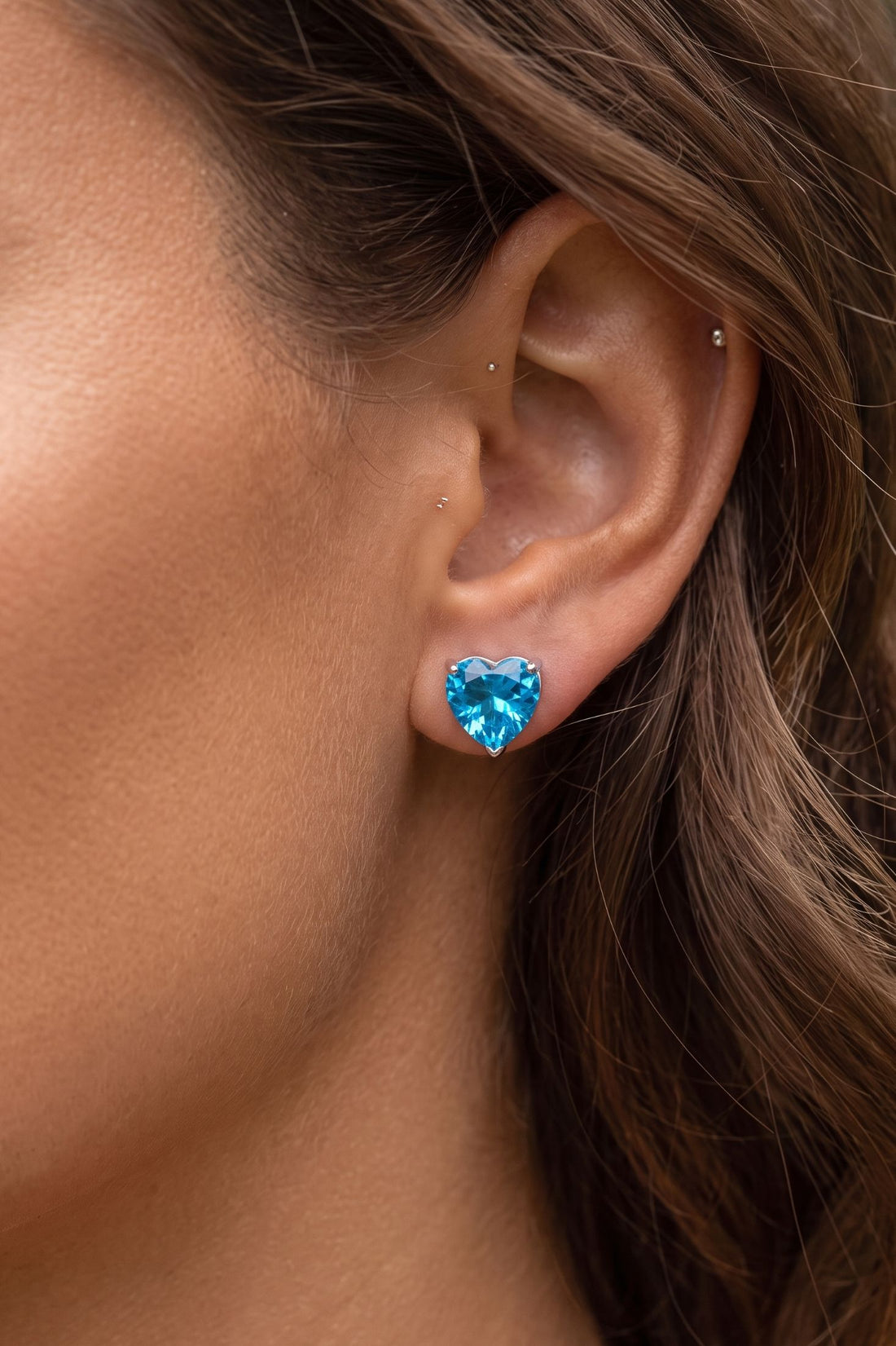 Blue heart gemstone stud earring on ear with silver post and back