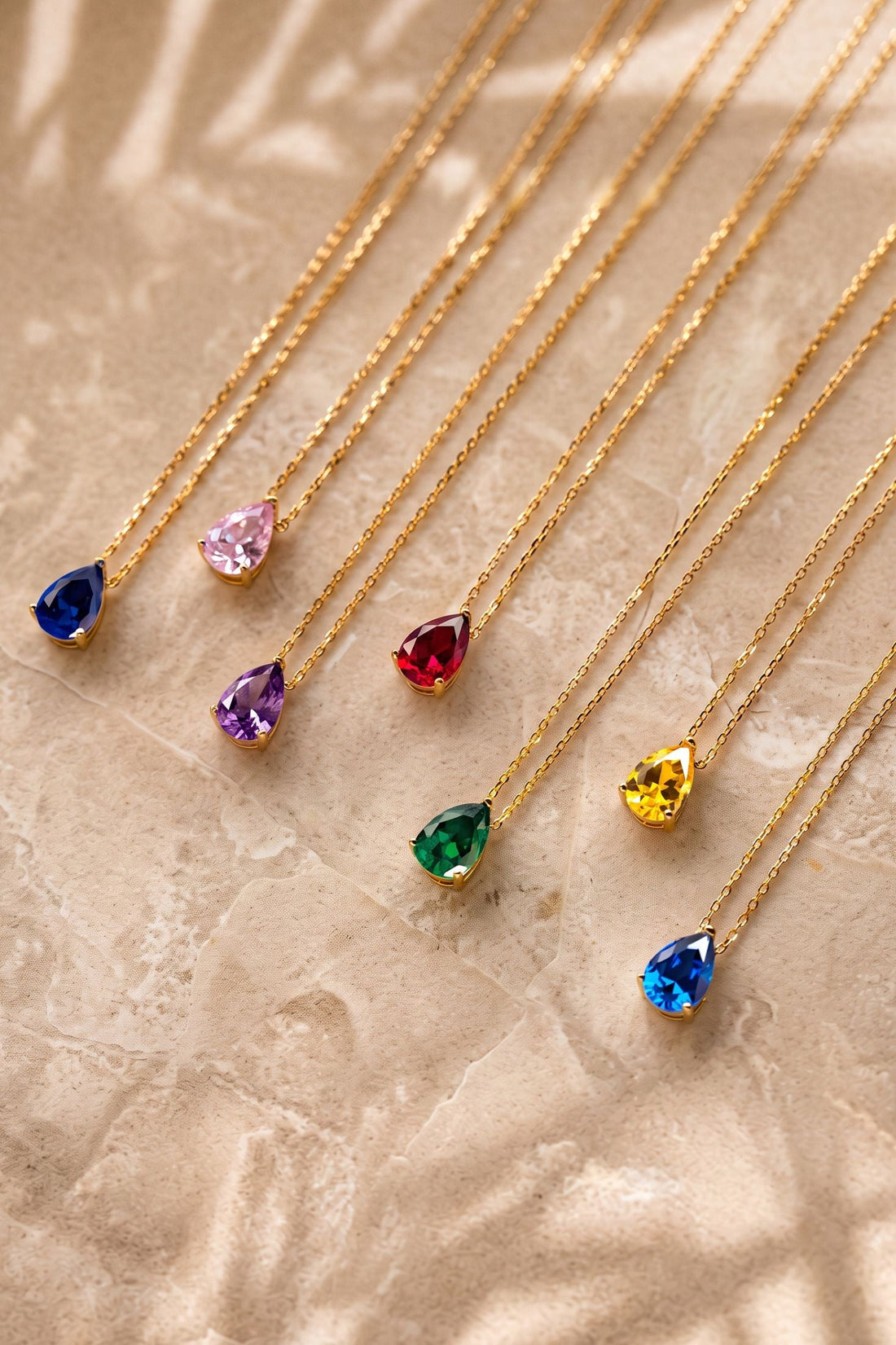 Layered gold chain necklace with multicolor teardrop gem pendants