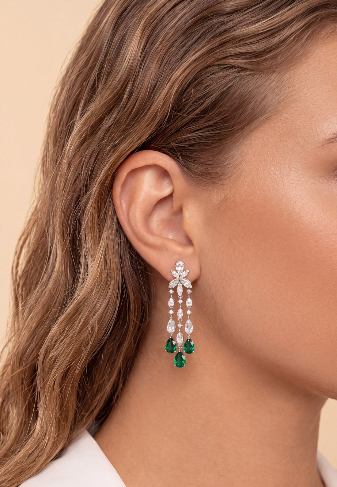 Silver chandelier earrings with green teardrop drops and crystal detailing at ear