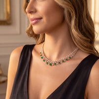 Gold emerald teardrop necklace detail on model, layered across the collarbone