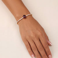 Ruby oval gemstone tennis bracelet in gold on a model's wrist