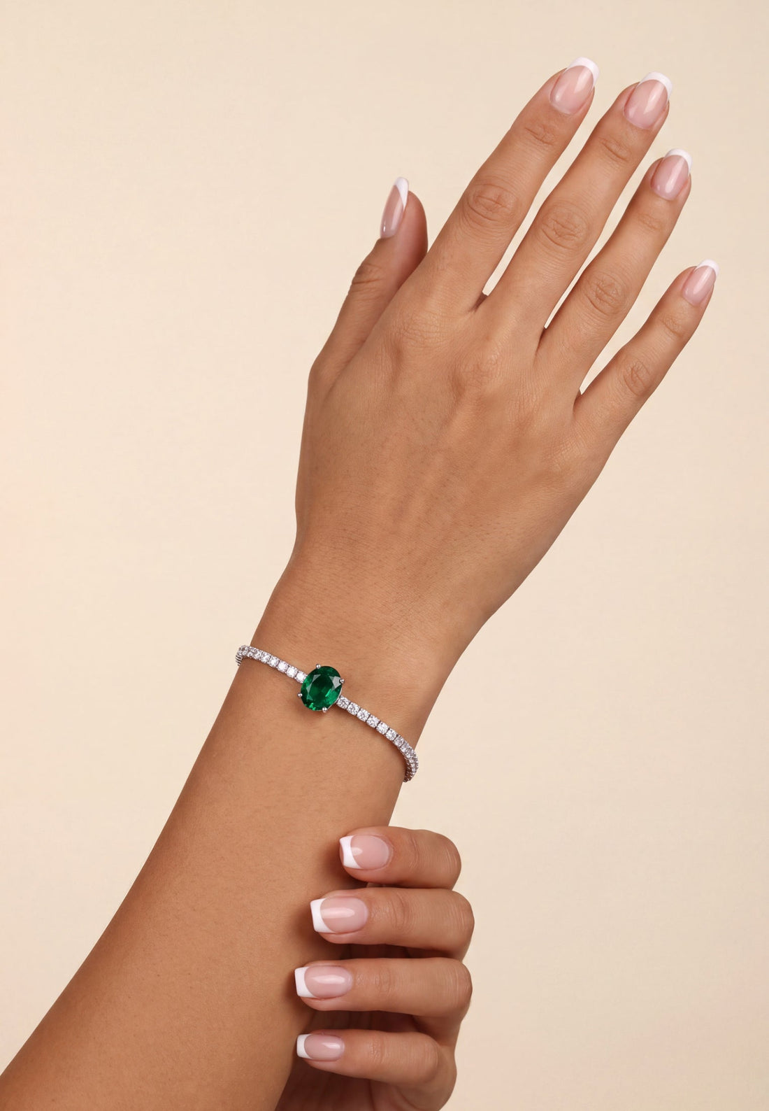 Silver tennis bracelet on wrist with emerald green oval center gemstone and white stones
