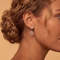 Silver clover flower drop earrings with open pointed petals and small center gem.