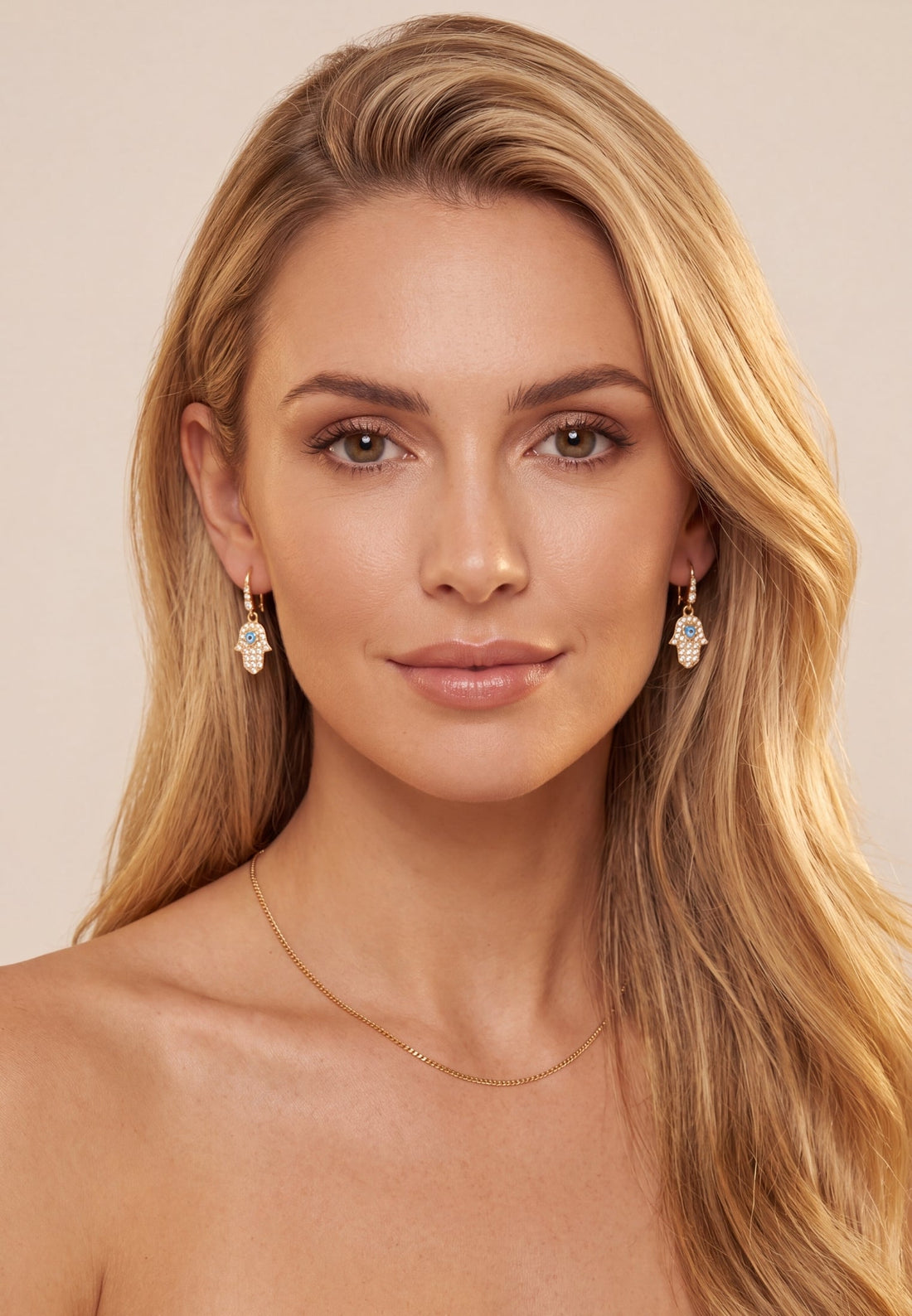 Gold hamsa drop earrings worn, dangling hand charm with blue eye and stones